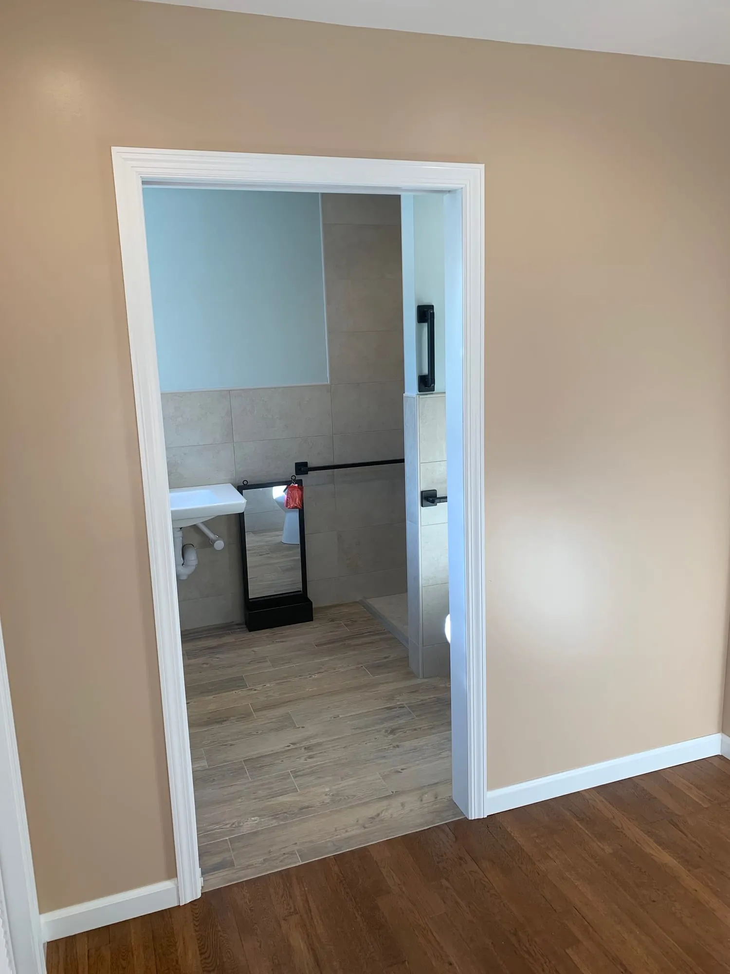 Wide doorway opening into the bathroom with wood-look floor tile