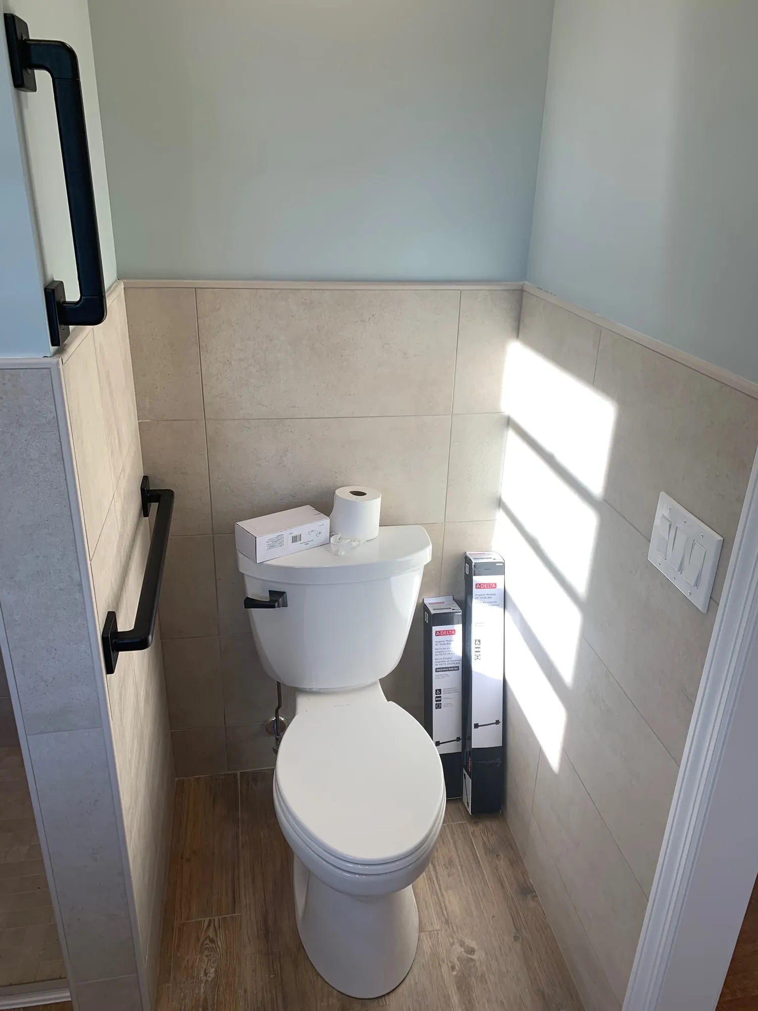 Toilet area with grab bars and tile wainscot