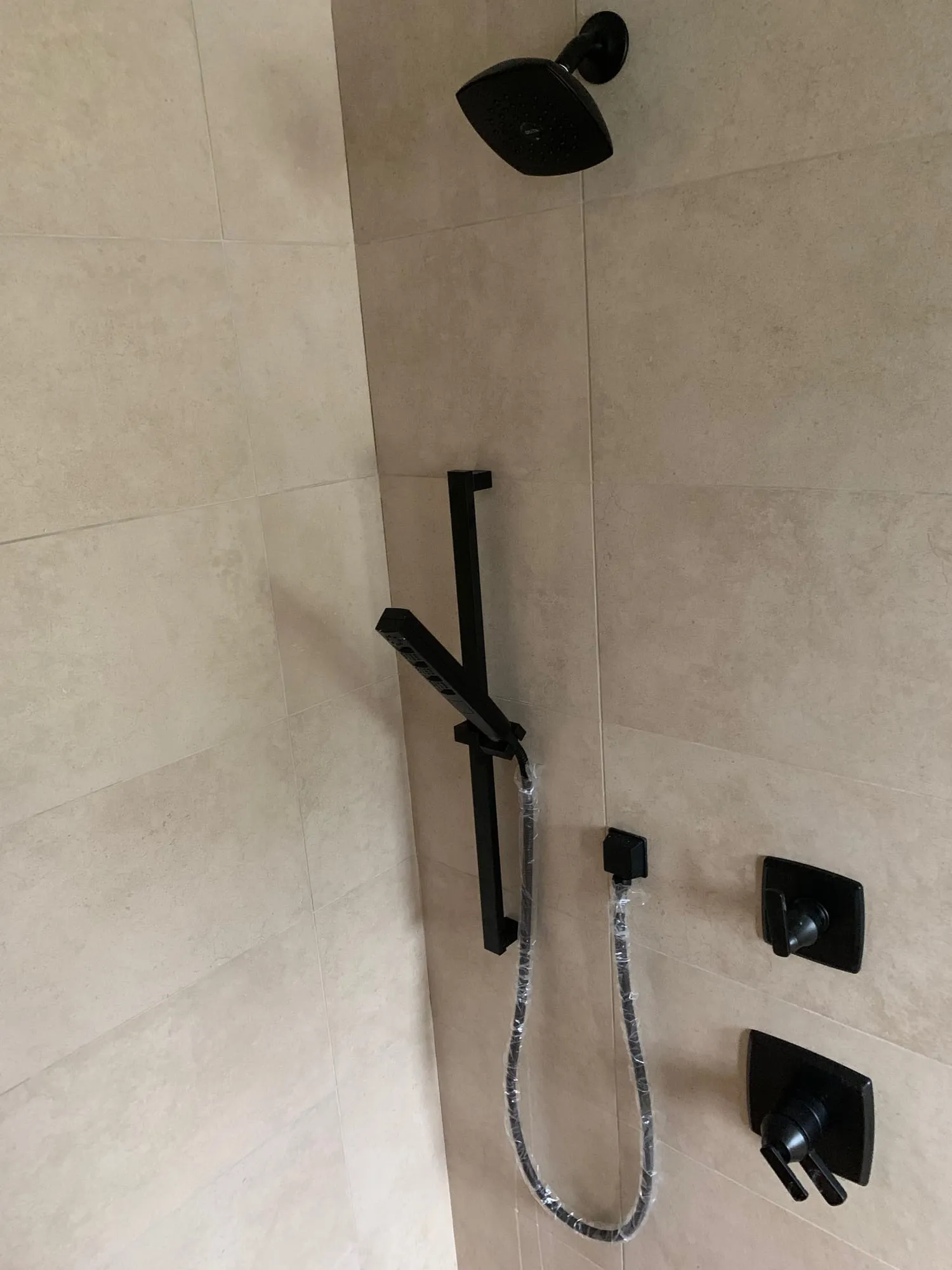 Shower valve and handheld shower installed in large-format tile, before the grab bars