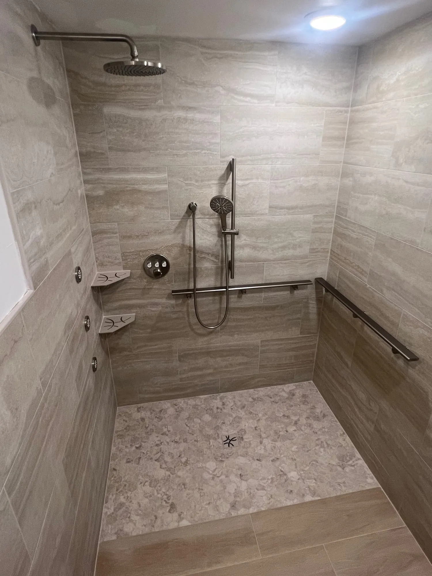 Wide accessible shower with a continuous grab bar and multiple body sprays