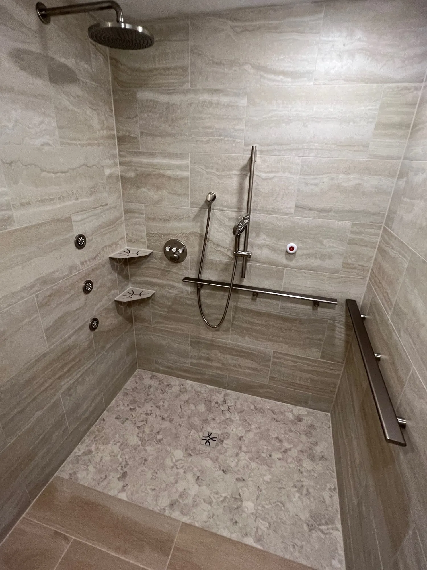 Large walk-in shower with stone-look tile walls and a pebble mosaic floor