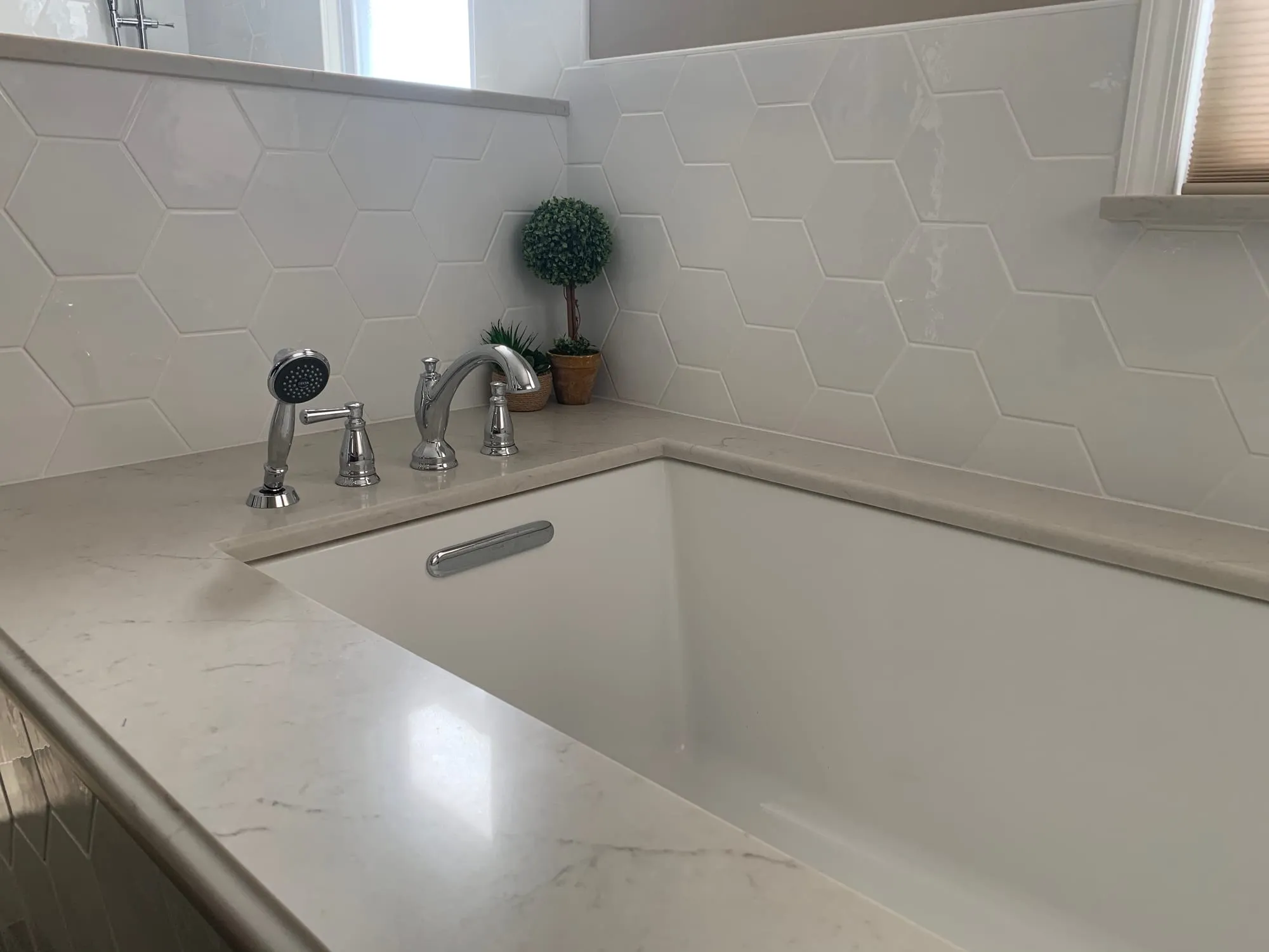 Deck-mounted tub filler and hand shower on a stone tub deck