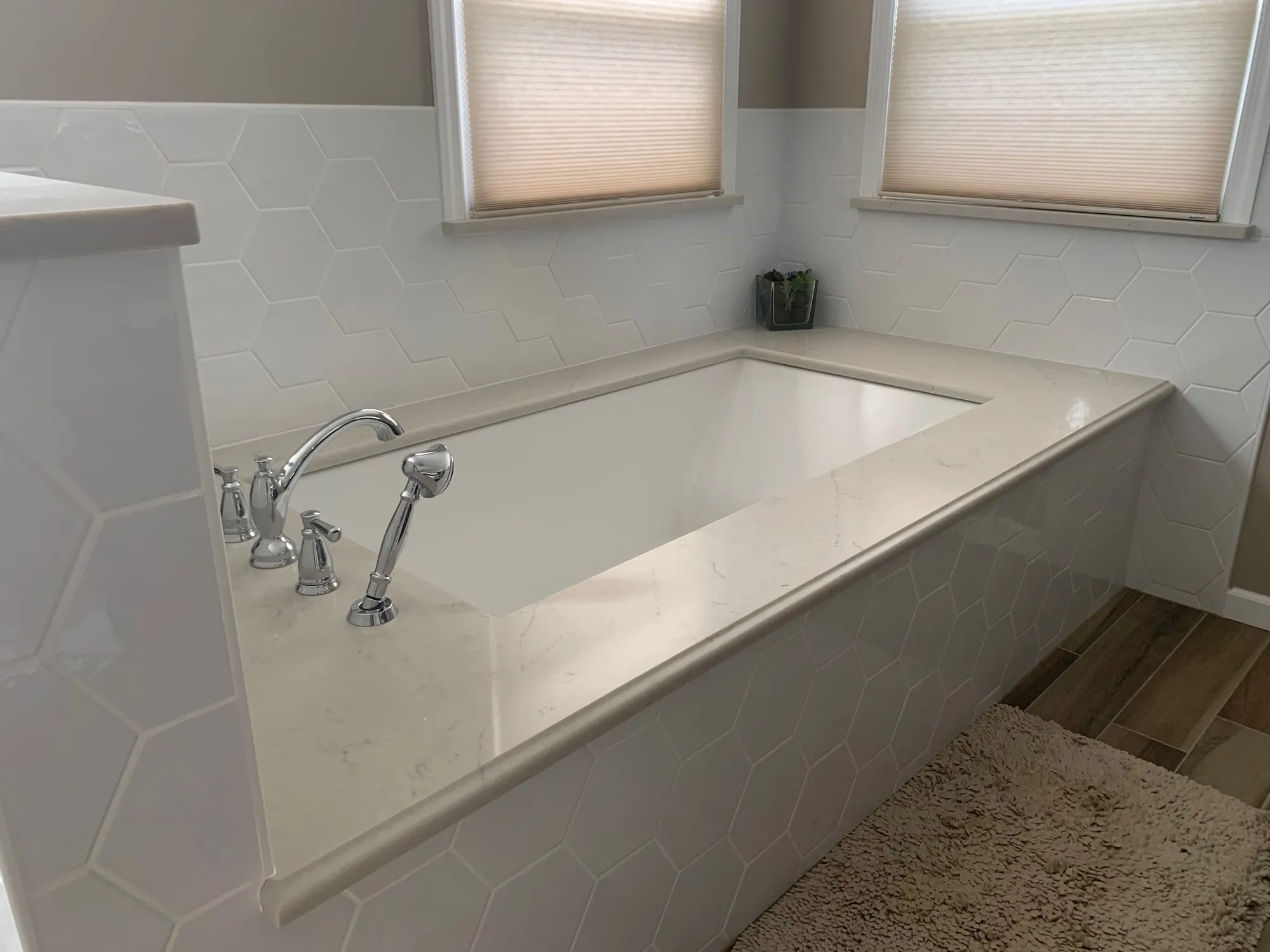 Soaking tub with a stone deck below a pair of windows