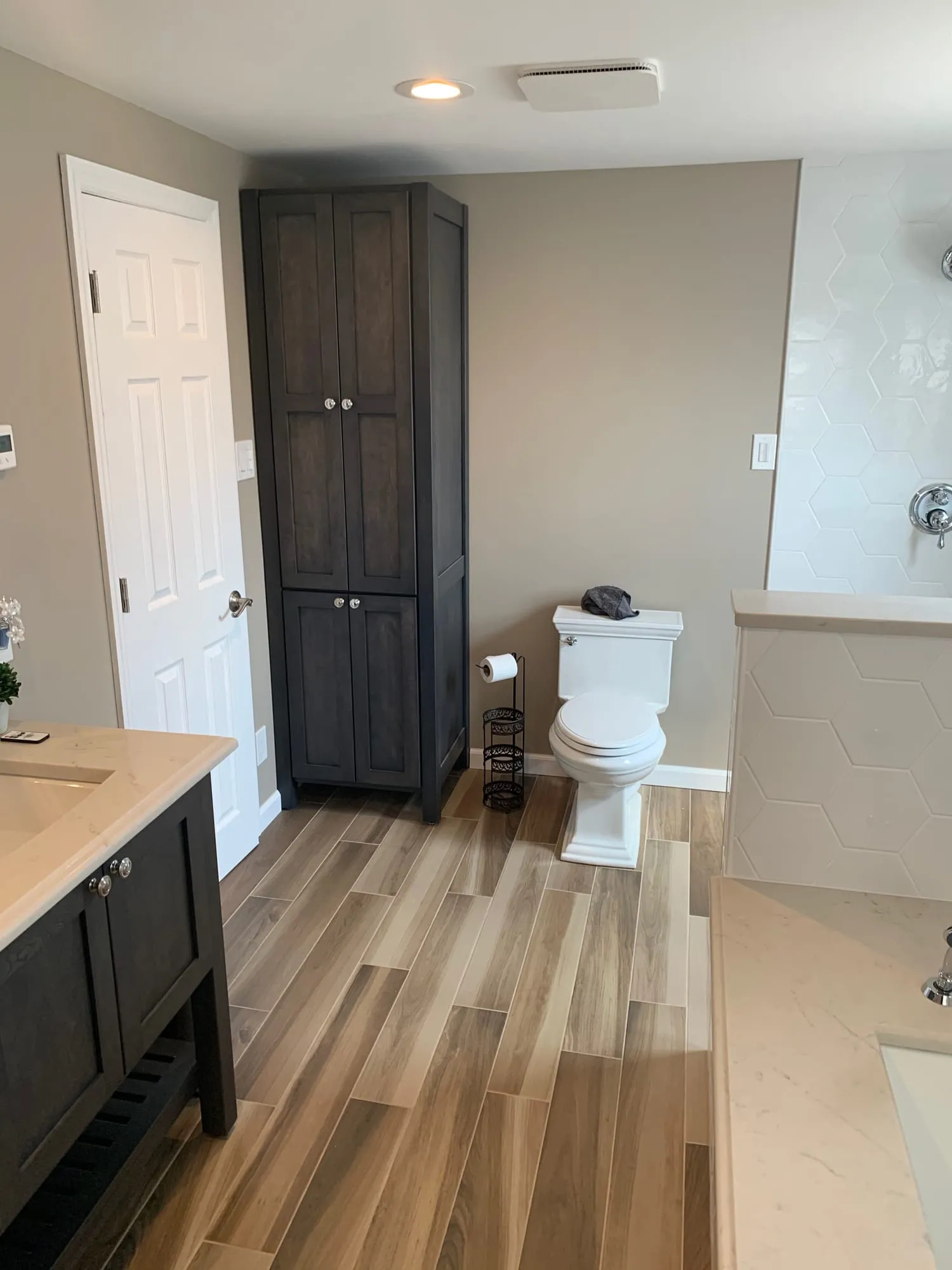 View past the vanity to a tall linen cabinet and toilet