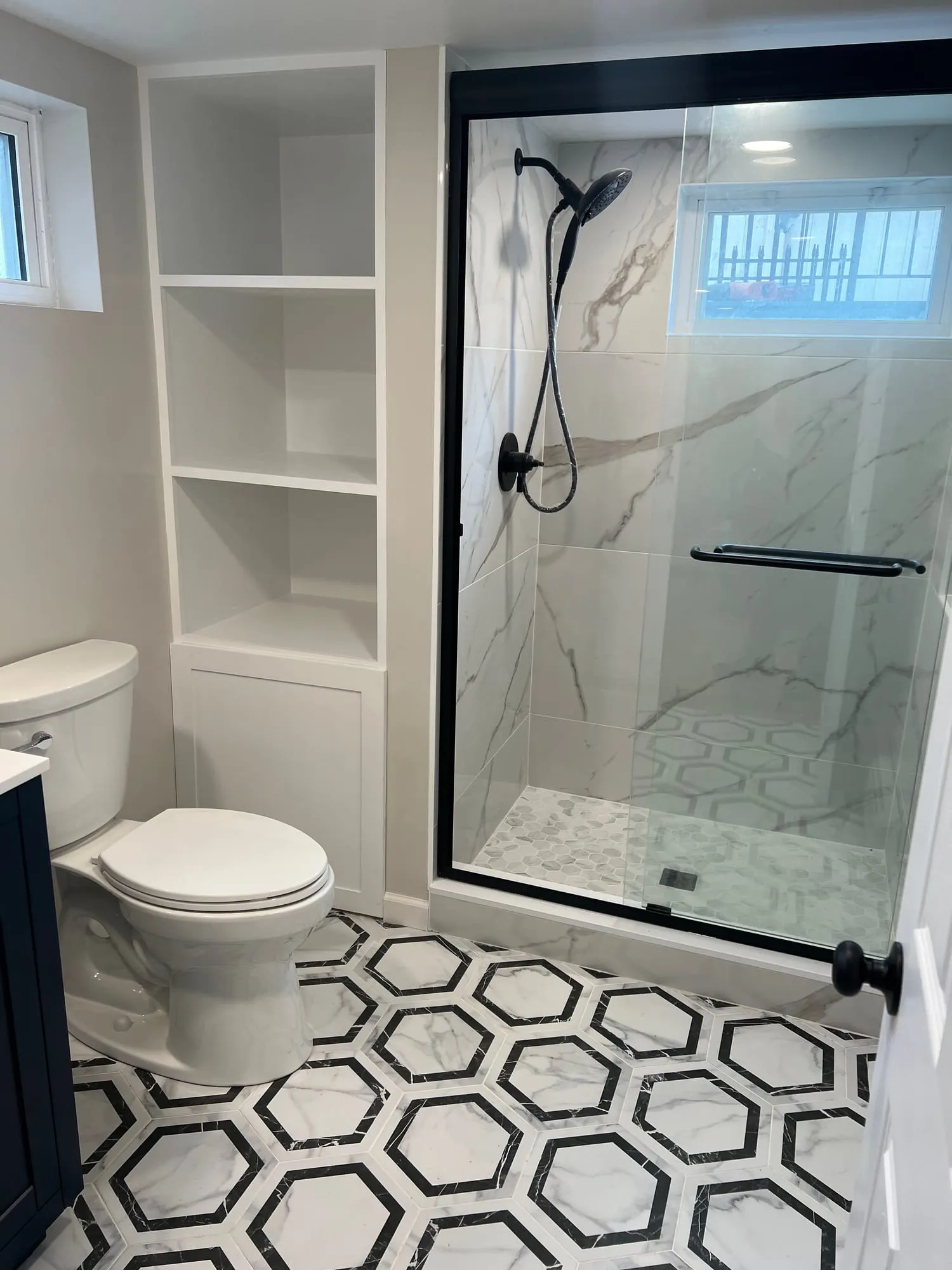Shower with marble-look wall tile, black-framed glass and built-in shelving