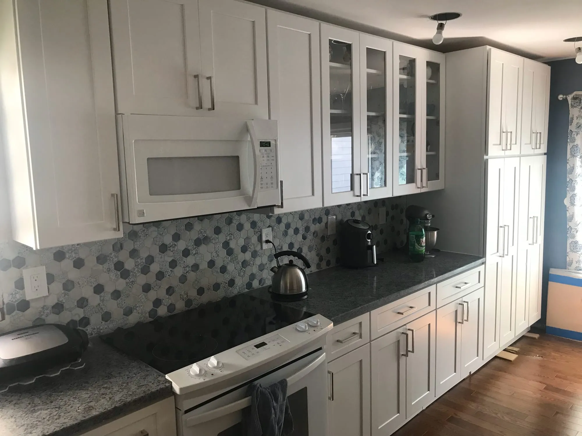 Range wall with white cabinetry, gray mosaic backsplash and dark speckled countertops