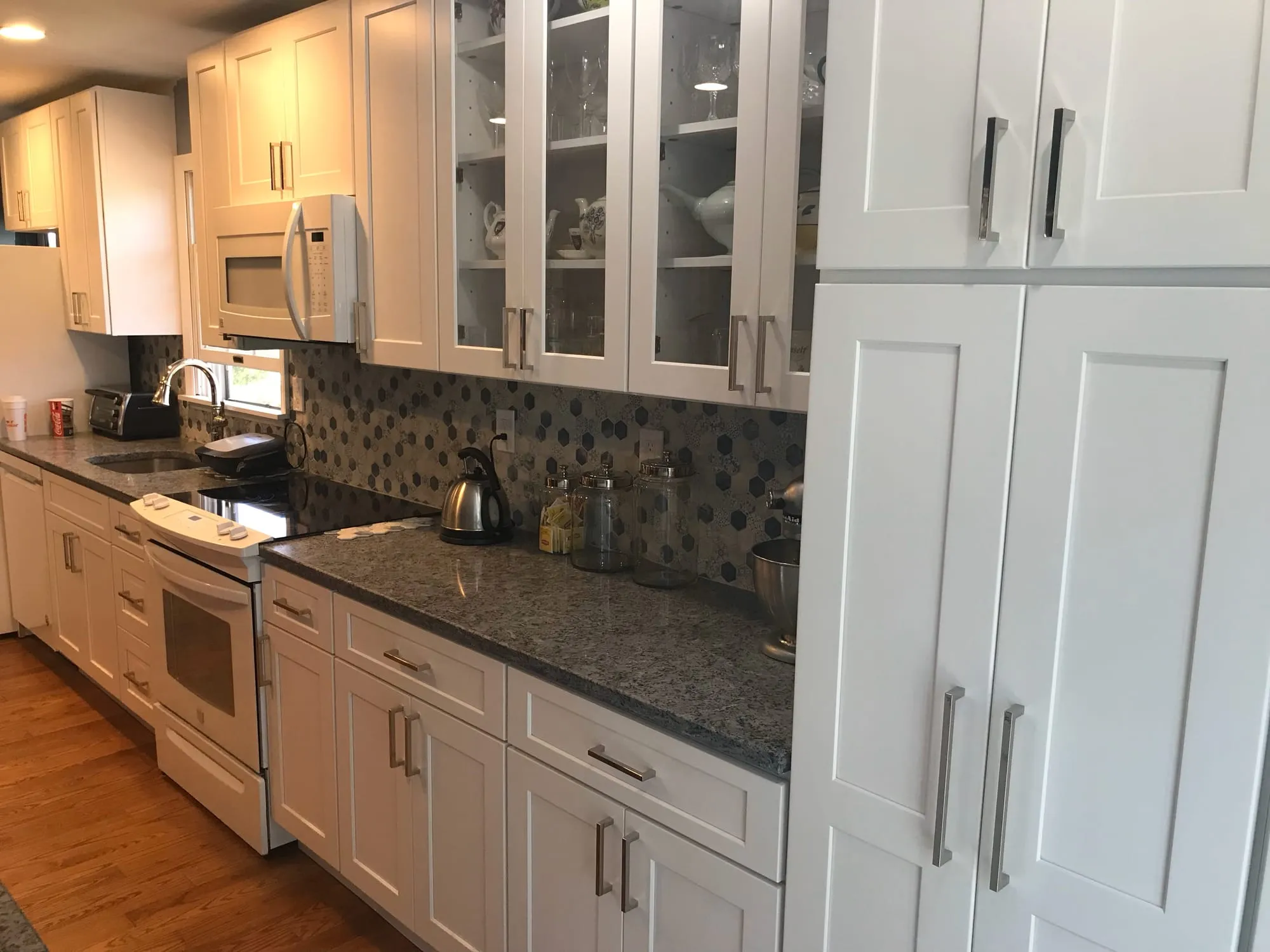 Tall white pantry cabinets beside the range run, with hardwood flooring throughout