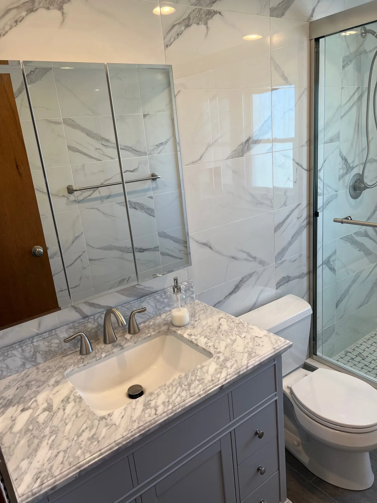 Bathroom with marble-look wall tile, a gray vanity with marble top and a glass-enclosed shower
