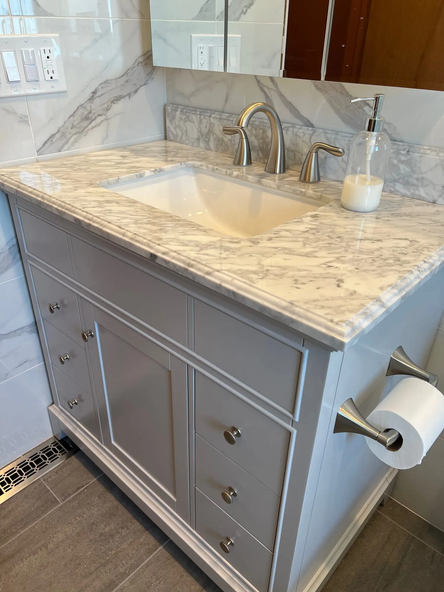Vanity detail with a brushed nickel faucet and veined stone countertop in Bethpage