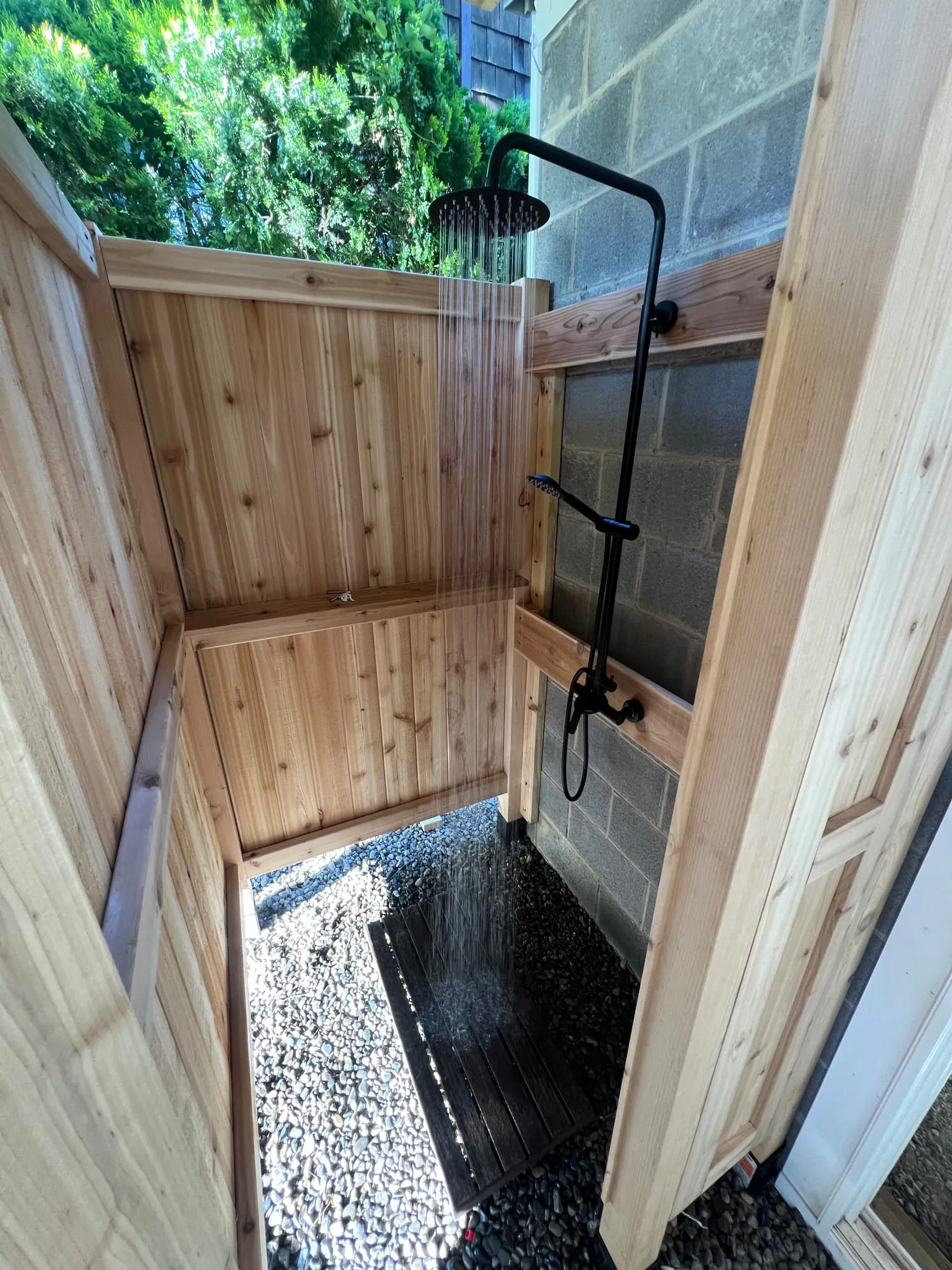 Custom cedar outdoor shower enclosure with a matte black rain head