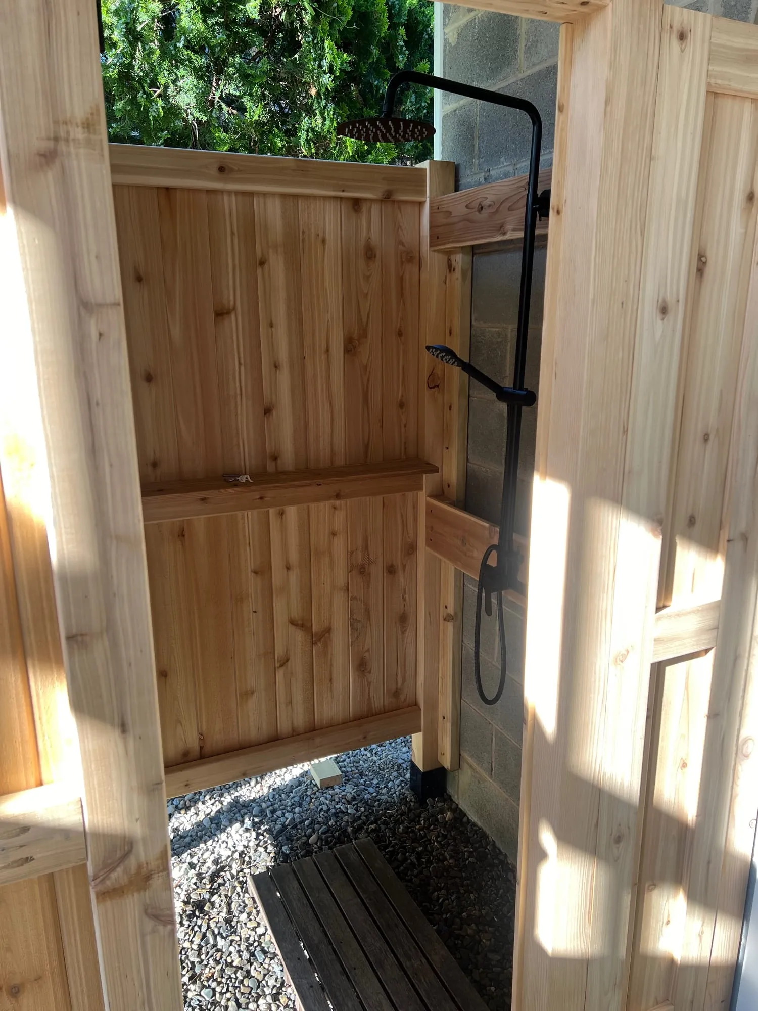 Interior of the cedar outdoor shower with a slatted floor over gravel