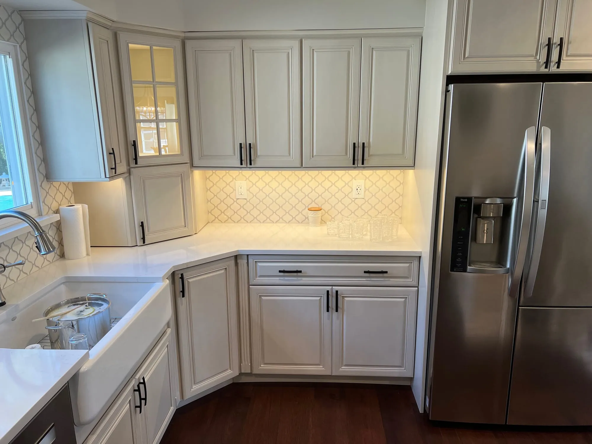 Kitchen corner with a lit glass-front cabinet and under-cabinet lighting in Dix Hills