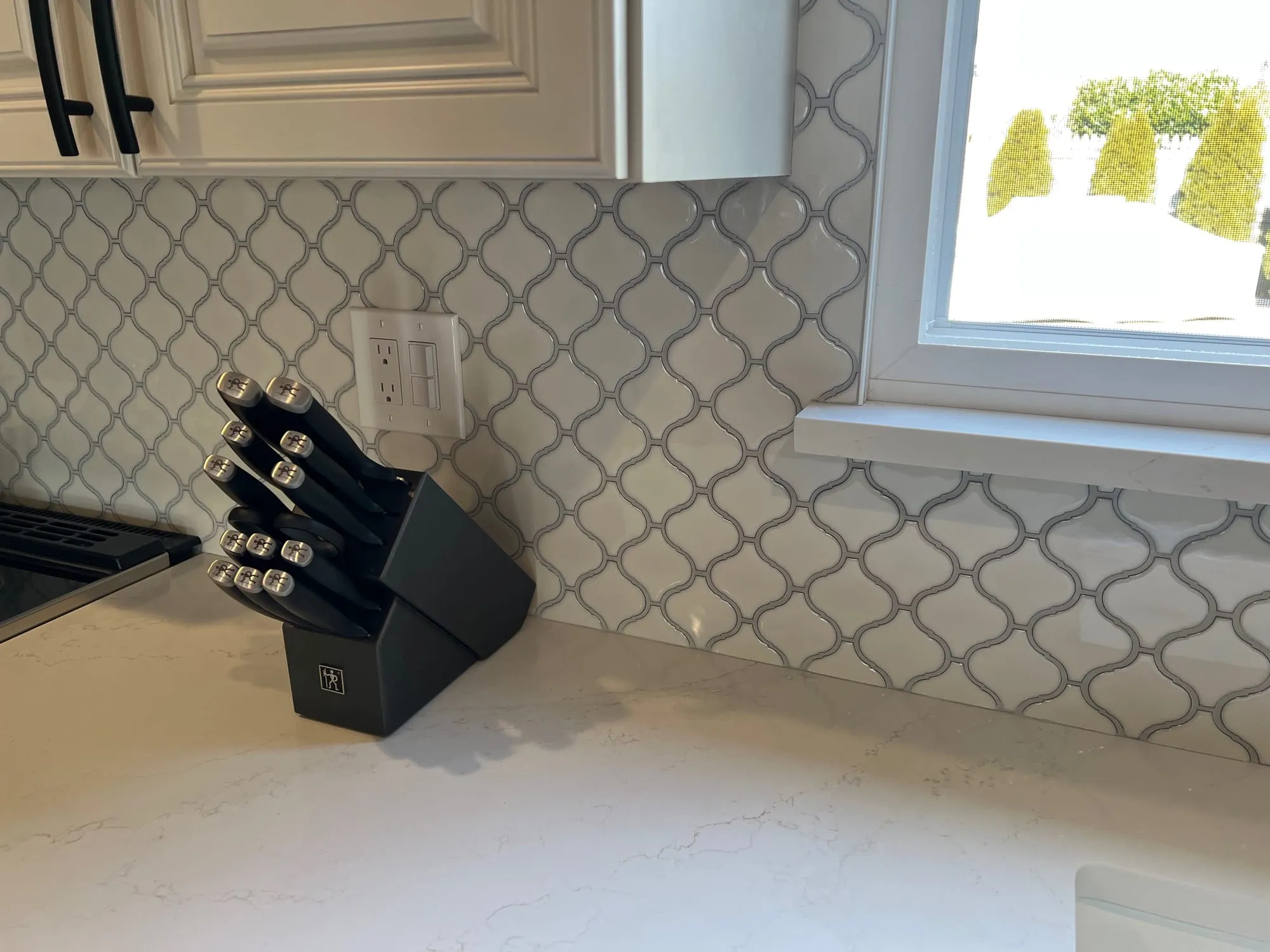 Arabesque backsplash tile cut cleanly around a window return and countertop