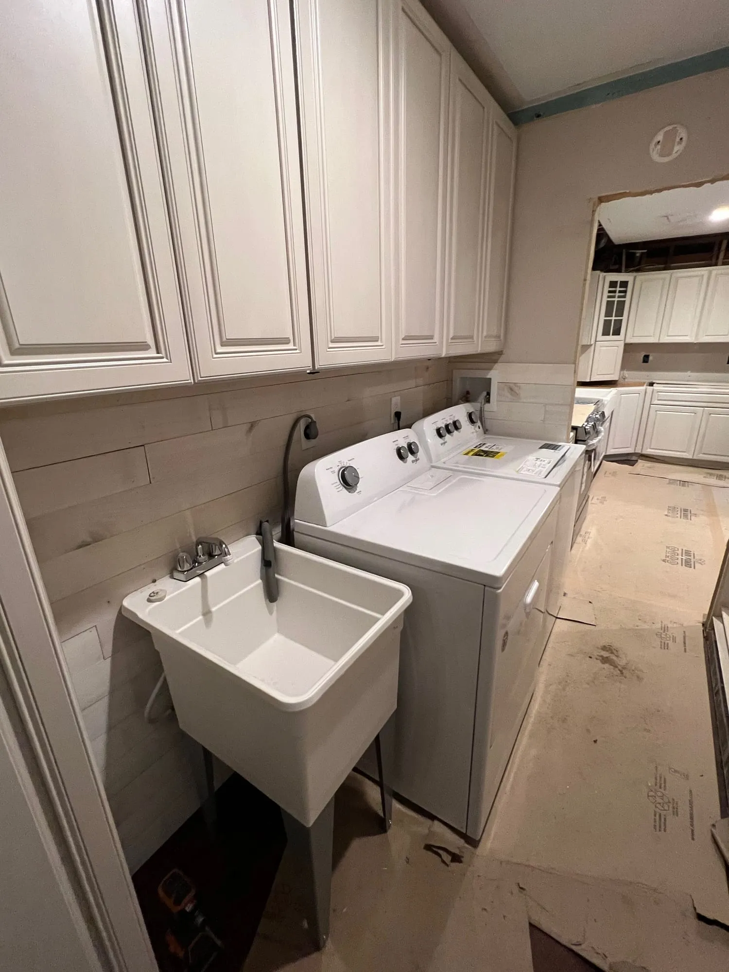 Adjacent laundry area in progress, with new cabinets and a plank wall finish installed