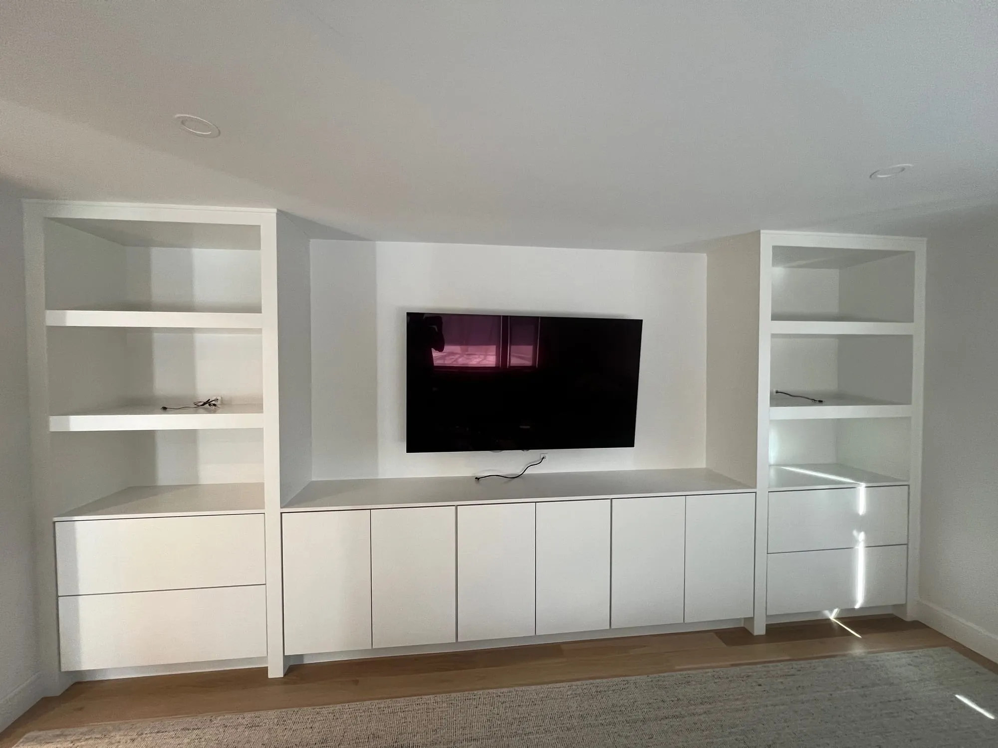 Finished East Hills basement with a built-in media wall and lit open shelving