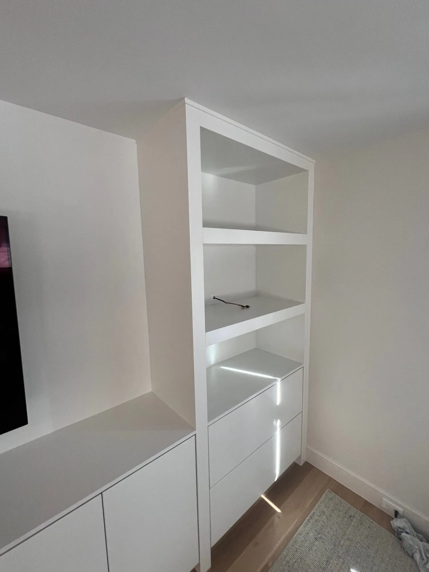 Lit open shelving at the end of a built-in media wall