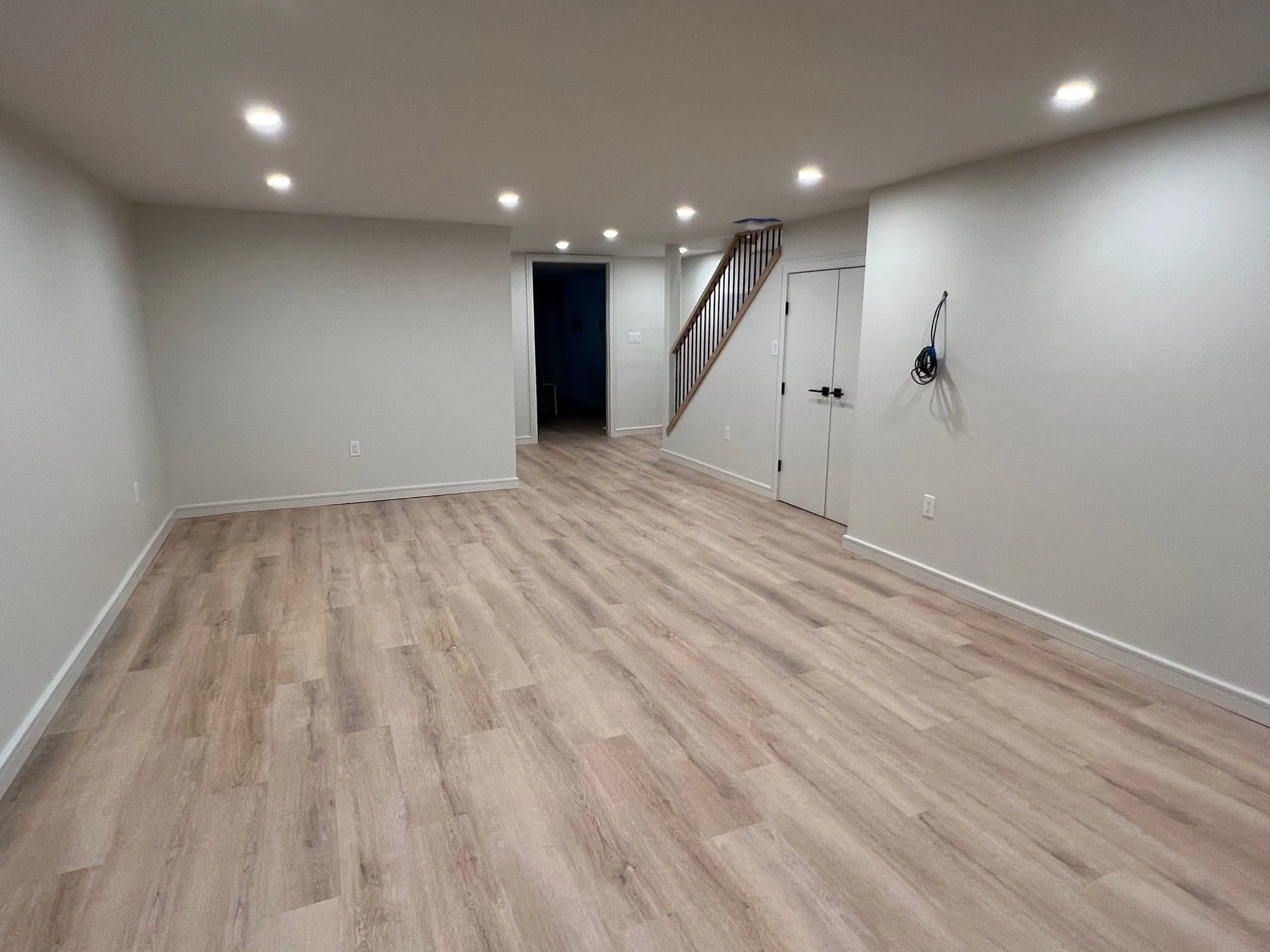 Finished basement with wood-look plank flooring and recessed lighting