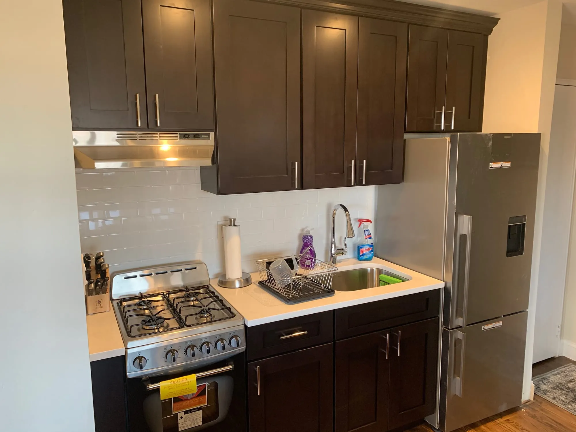 Renovated kitchen with espresso shaker cabinets, white countertops, a white tile backsplash and stainless appliances