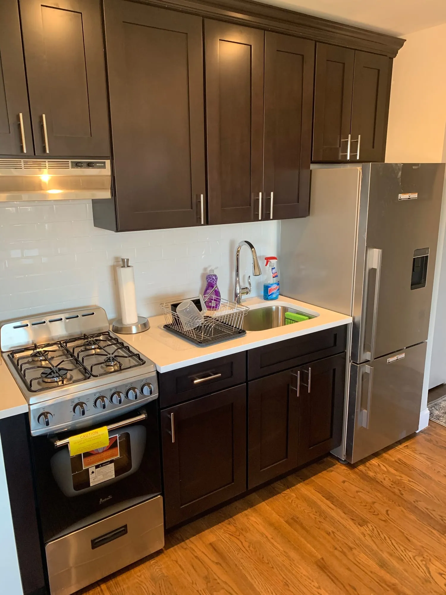 Espresso cabinets, white countertops and a stainless gas range in the renovated kitchen