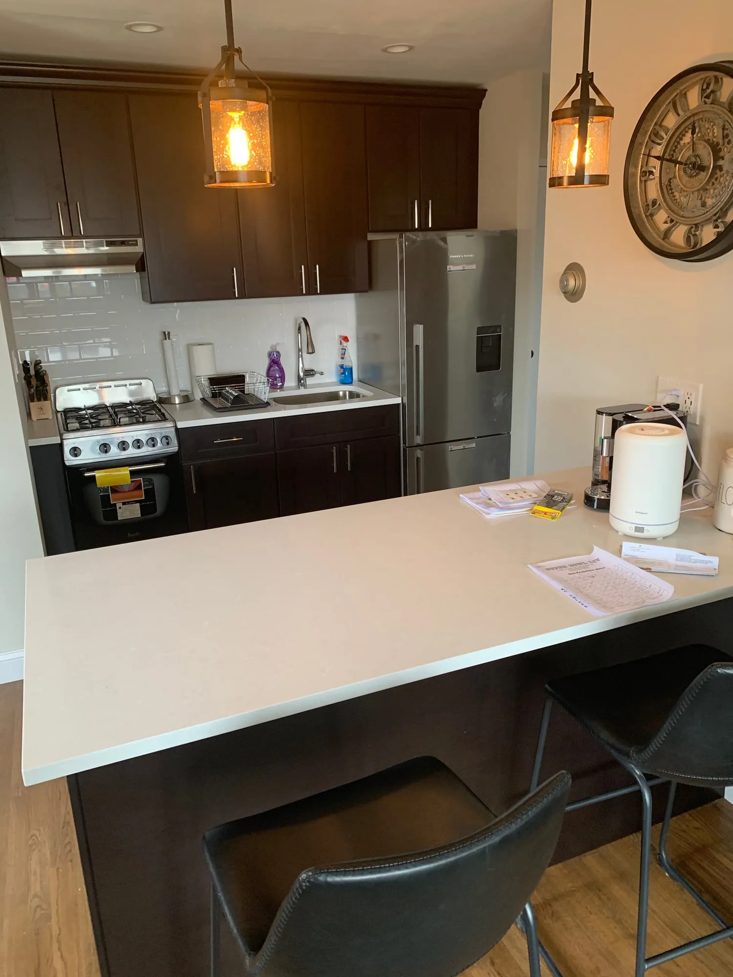 Kitchen peninsula with seating, a white countertop and pendant lighting