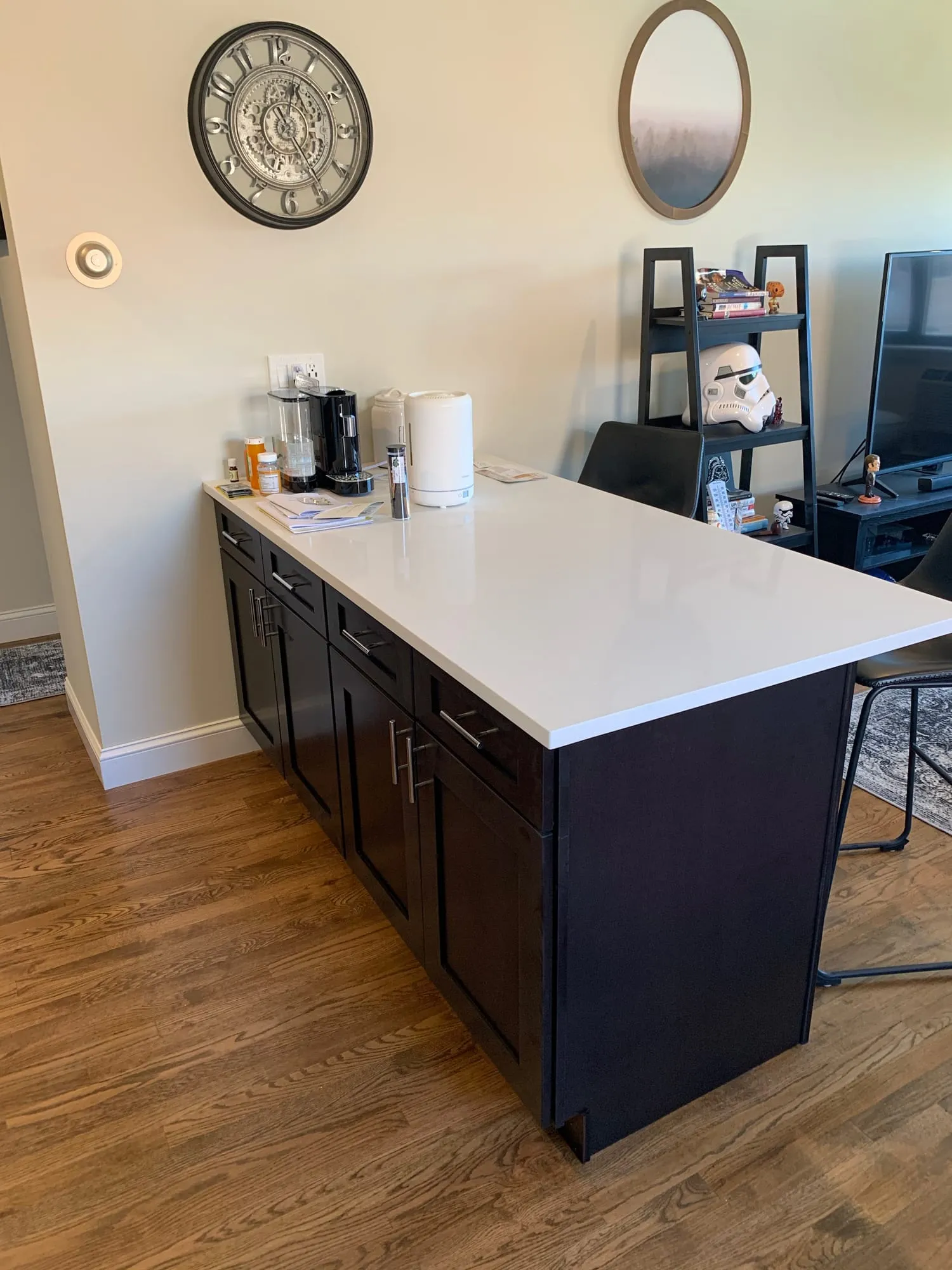 Dark cabinet peninsula with a white countertop overlooking the living area