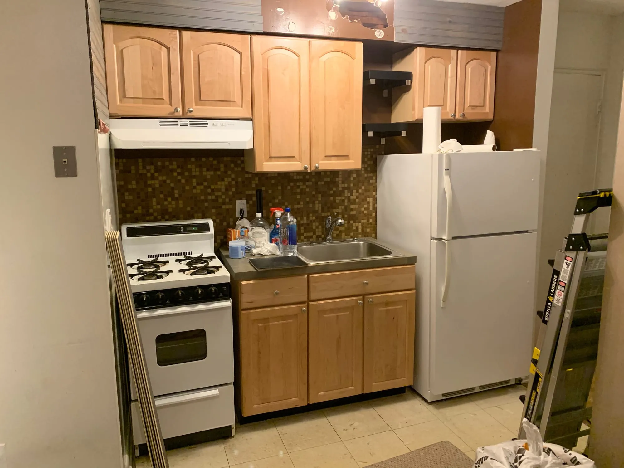 The original kitchen before renovation, with oak cabinets and a dated mosaic backsplash