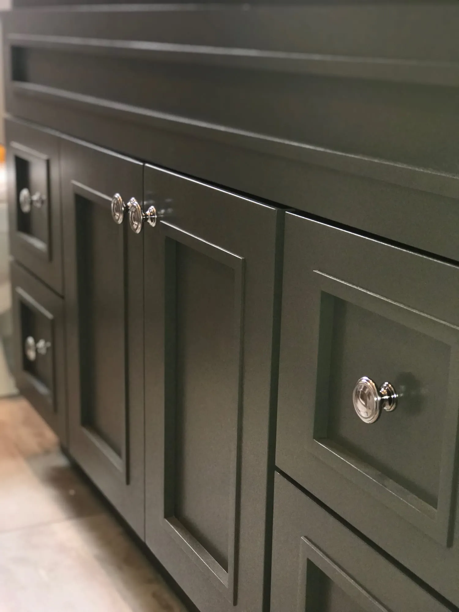 Dark gray vanity with raised-panel doors and glass knobs