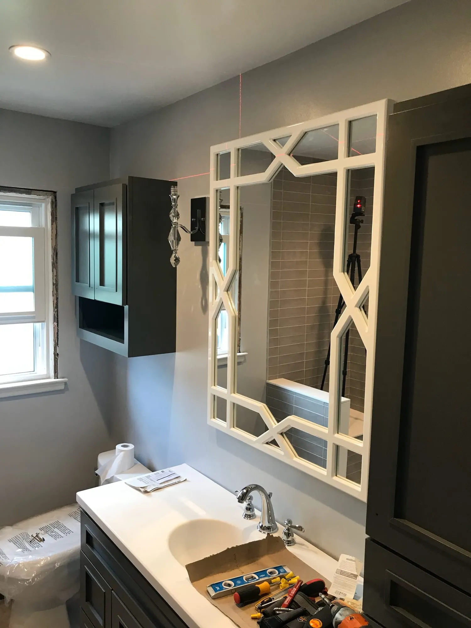 Vanity and lattice mirror installed while finishing work continues