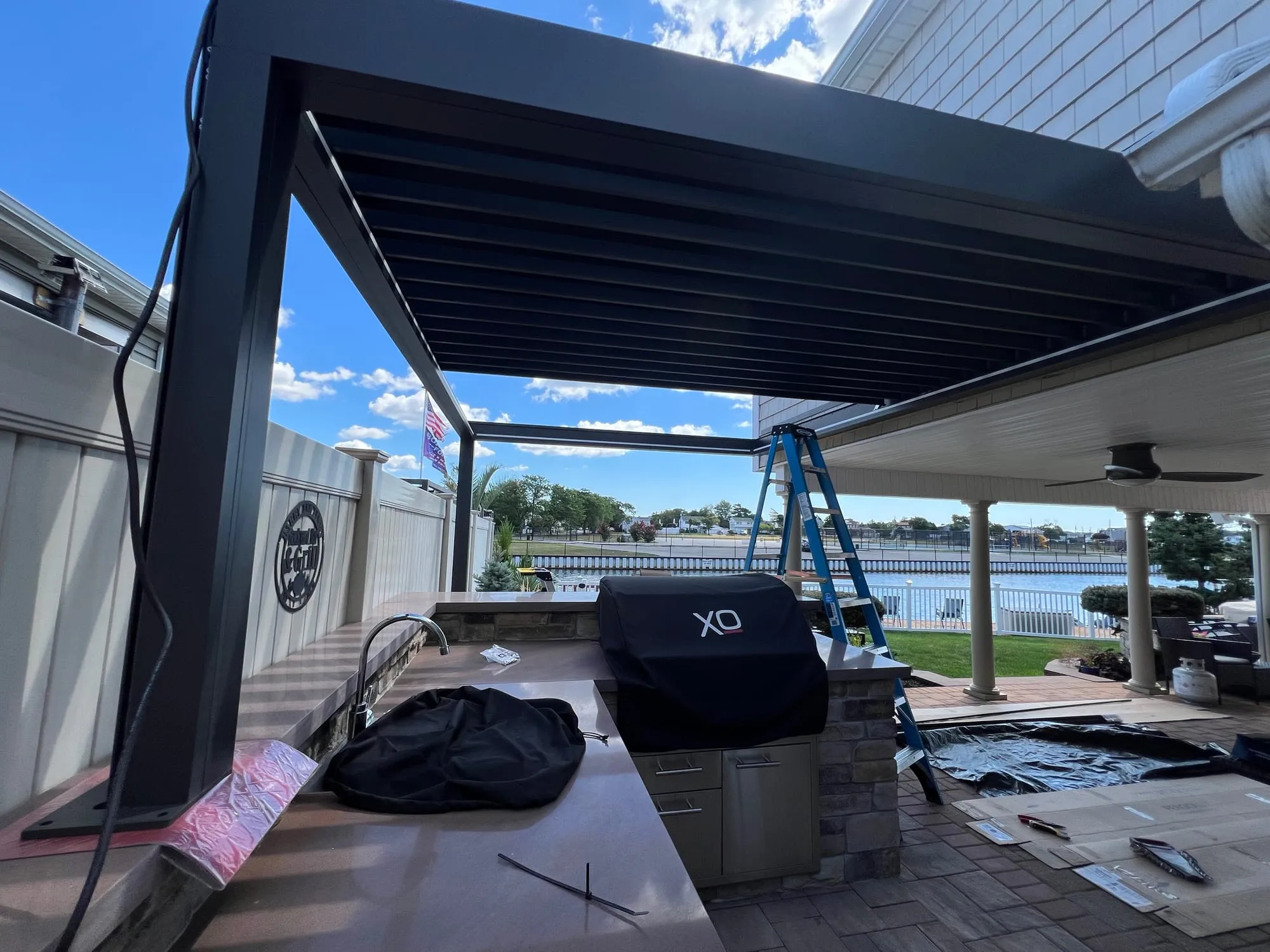 Louvered aluminum pergola over a paver patio and outdoor kitchen