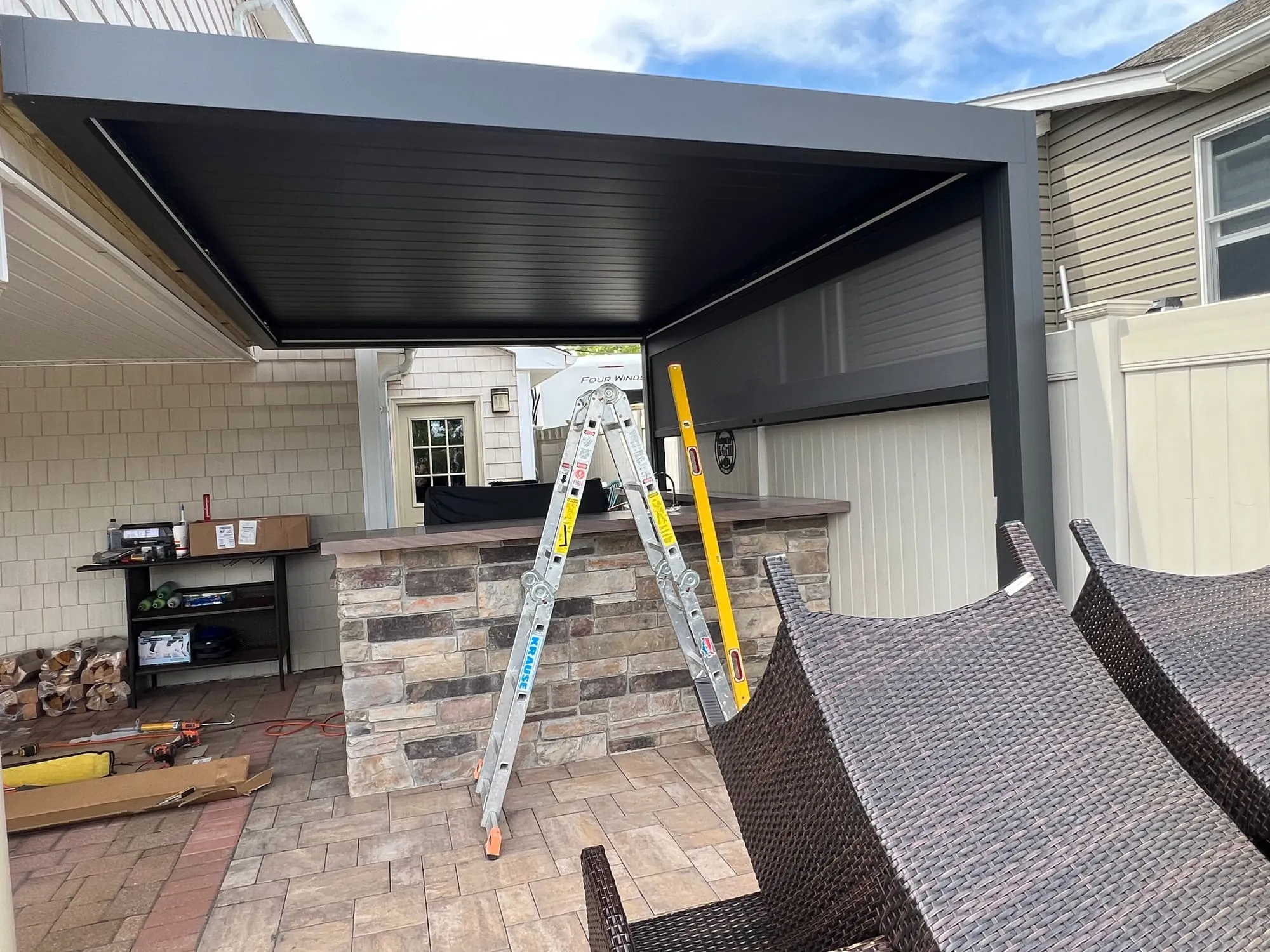 Dark aluminum pergola frame above an outdoor kitchen island