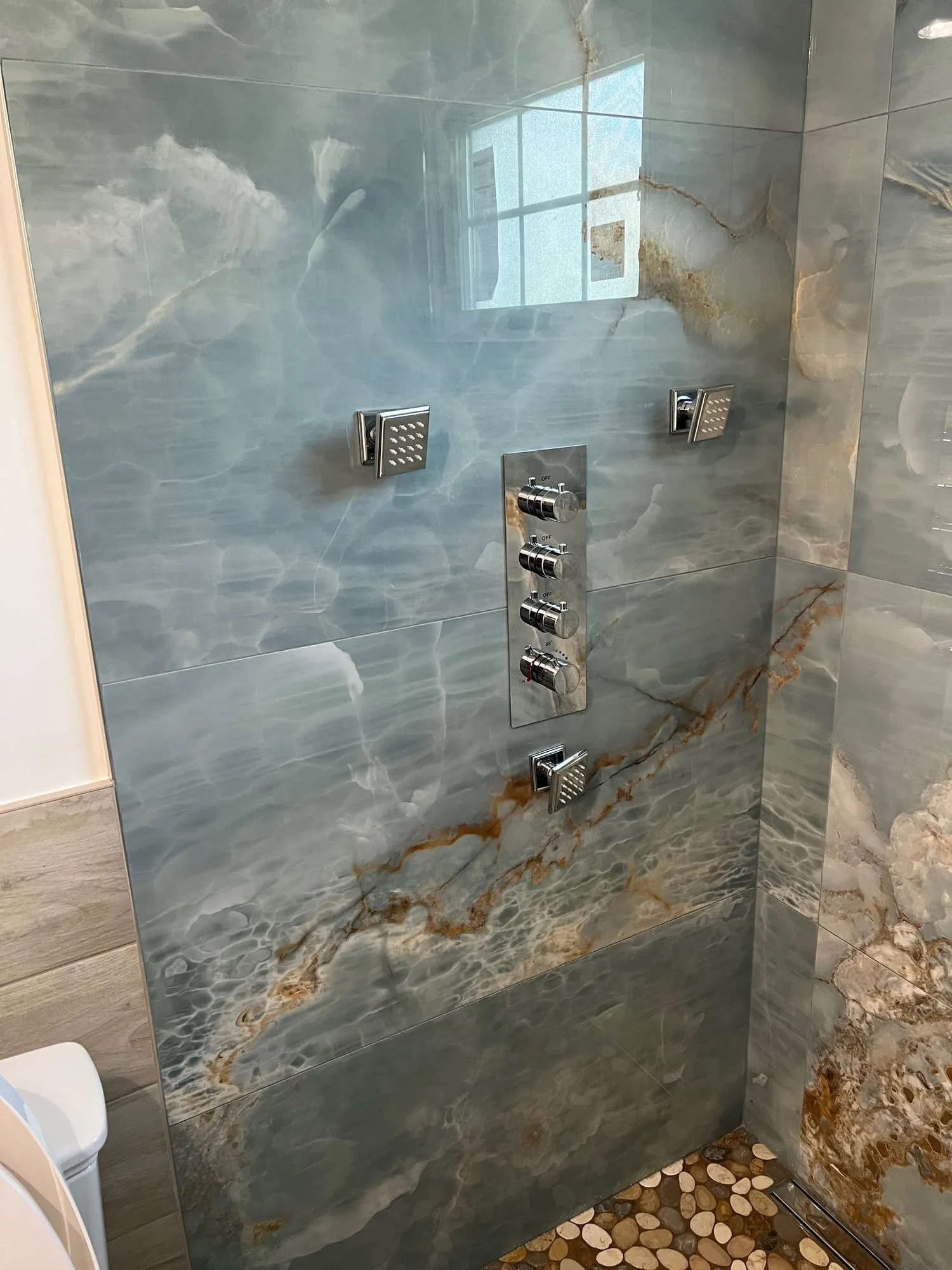 Shower control column with body sprays set into blue onyx-look slab tile