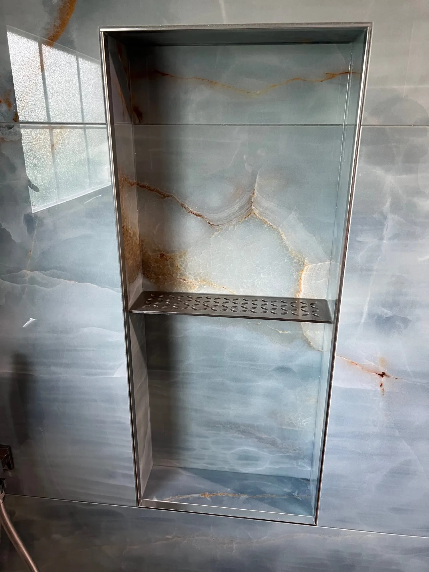 Floor-to-ceiling shower niche in blue onyx-look porcelain