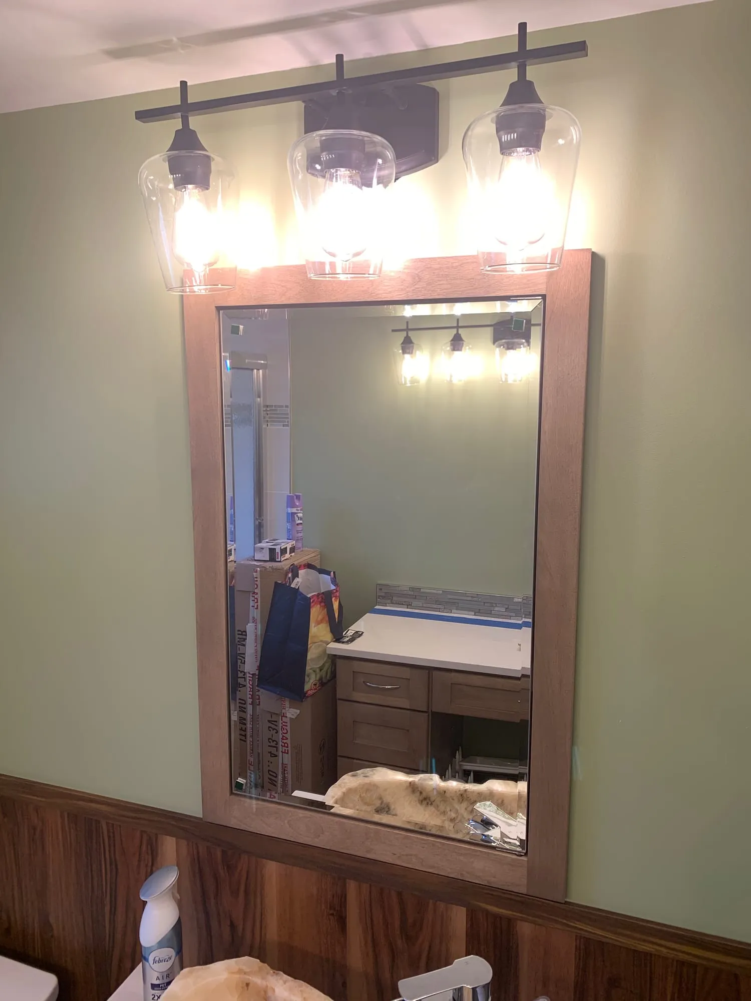 Vanity mirror with a three-light fixture above wood wainscoting