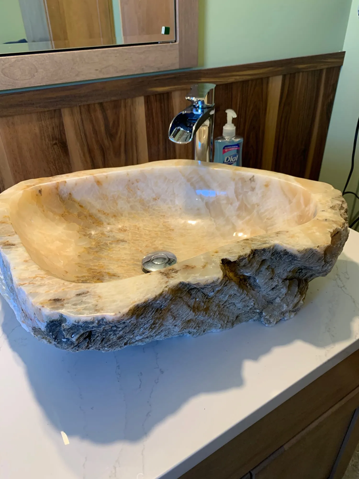 Natural stone vessel sink in front of wood wainscoting