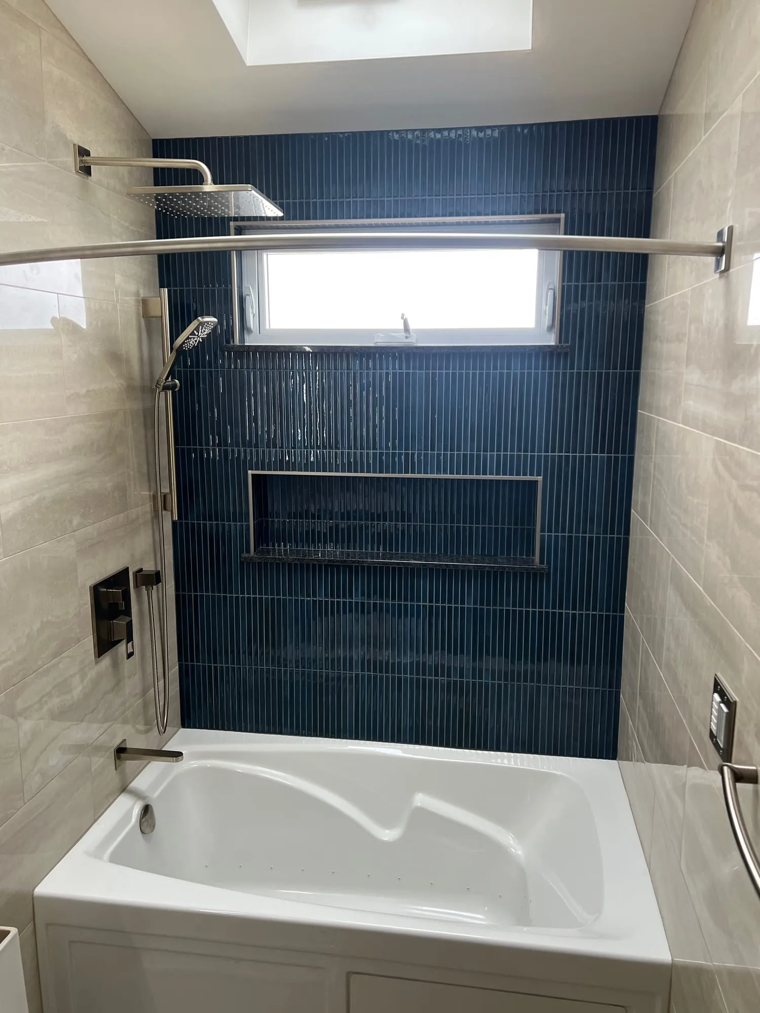 Navy glazed tile accent wall with a long niche above a soaking tub