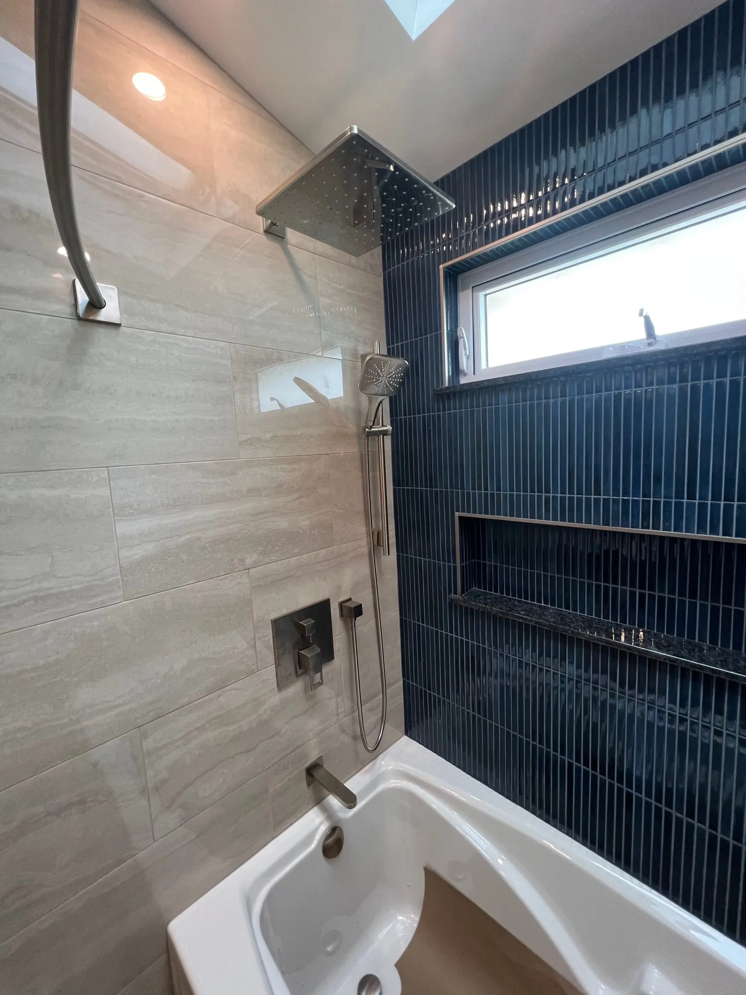 Rain shower head and navy stacked tile above the tub