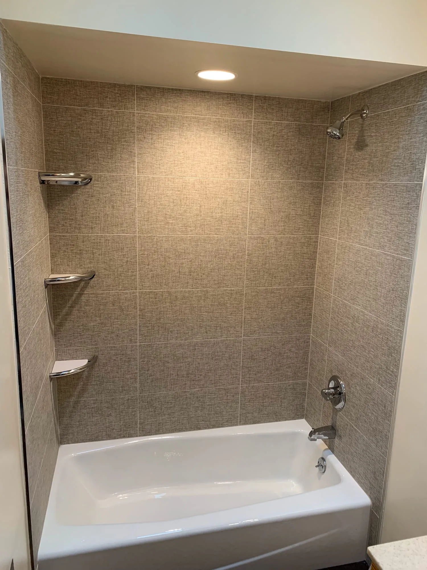 Replacement tub with a stone-look tile surround and corner shelves