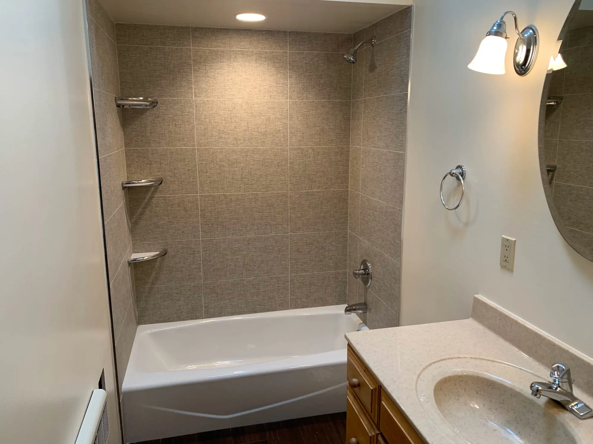 Tub surround beside the vanity and mirror